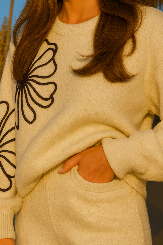 Elegant neutral two-piece knit outfit styled with a structured handbag at golden hour